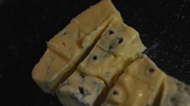 Kesme tahtasındaki Danimarka peyniri küpleri. 4K video. Üst görünüm