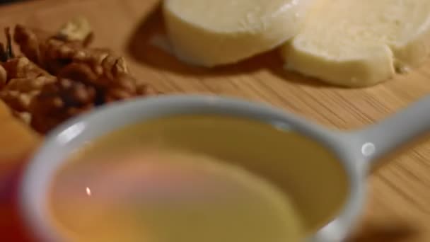 Mozzarella cortada en rodajas en una bandeja de madera con miel, nueces griegas, cubos de queso cheddar y rodajas de jamón de cerdo como aperitivo sabroso y atractivo. Vídeo 4K. Cronograma — Vídeo de stock