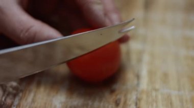 Tahtada mutfak bıçağıyla kırmızı kiraz domateslerini dilimlemek, sevgililer günü için kalp şeklinde pizza hazırlamak. 4K video