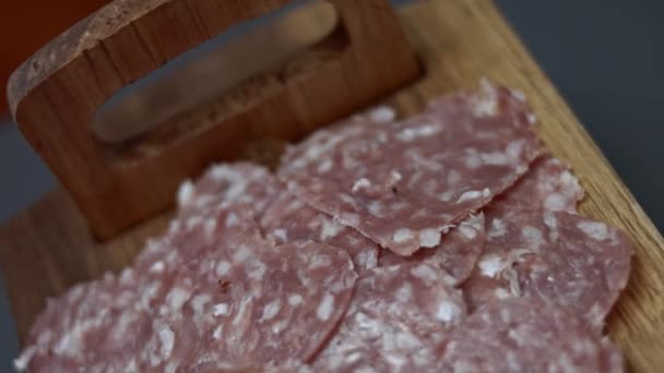 新鮮なイタリアのスライスされたサラミソーセージとモッツァレラチーズは、木製のトレイテーブルの上にハート型のピザを用意しています。4Kビデオ。トップ表示 — ストック動画