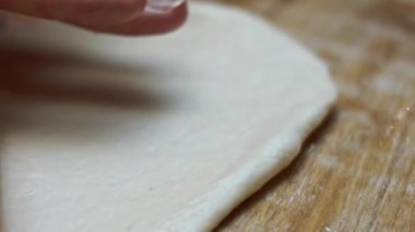 Tahta kesme tahtasının üzerinde pizza için taze hamur hazırlıyorum. Sevgililer Günü için kalp şeklinde pizza hazırlıyorum. Sevdiğim biri için. 4K video. Makro görünüm