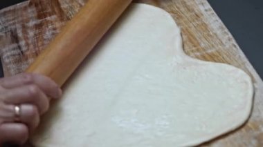 Tahta kesme tahtasının üzerinde pizza için taze hamur hazırlıyorum. Sevgililer Günü için kalp şeklinde pizza hazırlıyorum. Sevdiğim biri için. 4K video.