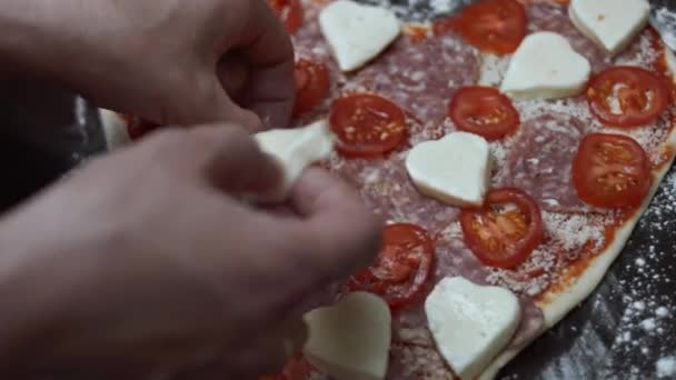 Szívalakú mozzarella hozzáadása a pizzához a sütőtálcán. Szívalakú pizzát készítek Valentin napra egy szerettemnek. 4K videó — Stock videók