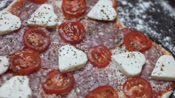 Draufsicht auf die rohe herzförmige Pizza auf dem Backblech. Die Zubereitung einer herzförmigen Pizza zum Valentinstag für einen geliebten Menschen. 4K-Video — Stockvideo