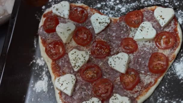 Καρυκεύματα πίτσα με μαύρο πιπέρι στο ταψί. Προετοιμασία καρδιά σχήμα πίτσα για την Ημέρα του Αγίου Βαλεντίνου για ένα αγαπημένο πρόσωπο. Βίντεο 4K. Άνω όψη — Αρχείο Βίντεο