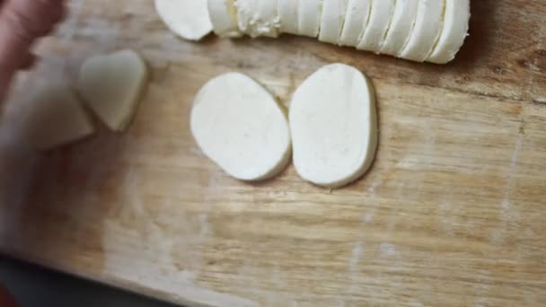 Mains féminines coupant des formes de coeur de fromage mozzarella sur une planche à découper en bois. Préparation de la nourriture pour la Saint-Valentin. Vidéo 4k, vue du dessus — Video
