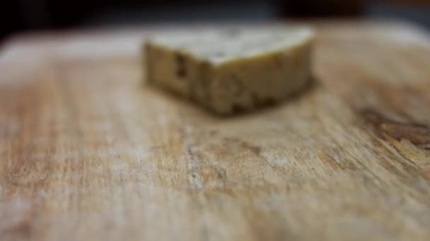 Δανέζικο μπλε τυρί. Κοντινό πλάνο του γυναικείου χεριού βάζοντας ένα κομμάτι τυρί μυτσέλα σε ένα ξύλινο ξύλο κοπής. Βίντεο 4K. Καλλιτεχνική σκοποβολή, αργή κίνηση — Αρχείο Βίντεο
