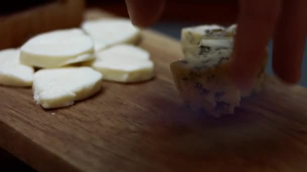 Queijo azul dinamarquês. Close-up de mão feminina organizando cubos de queijo mycella em uma mesa de bandeja de madeira. Vídeo 4K — Vídeo de Stock