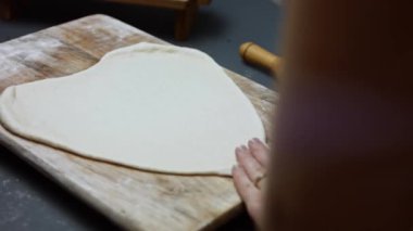 Tahta kesme tahtasının üzerinde ton balıklı pizza için taze hamur hazırlıyorum. Sevgililer Günü için kalp şeklinde ton balıklı pizza hazırlıyorum. 4K video