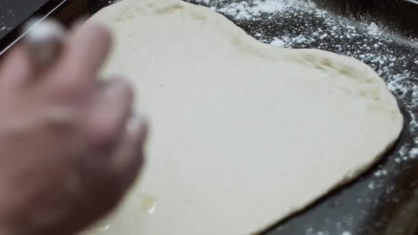 Olívaolajjal zsírozza a szív alakú tésztát, hogy tonhalas pizzát főzzön. A szív alakú tonhal pizza előkészítése Valentin-napra meglepetés ételként egy szerettünknek. 4K videó — Stock videók
