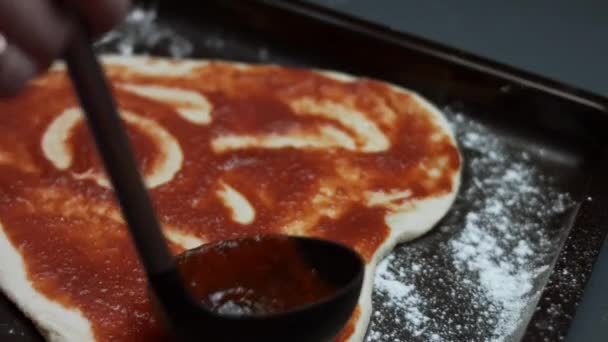 Rozsiewam sos pomidorowy nad pizzą. Przygotowywanie pizzy z tuńczyka w kształcie serca na Walentynki dla ukochanej osoby. Wideo 4K — Wideo stockowe