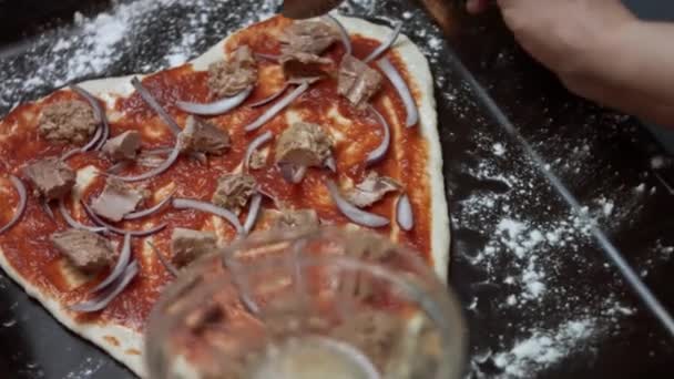 Rozrzucanie kawałków tuńczyka nad pizzą. Przygotowywanie pizzy z tuńczyka w kształcie serca na Walentynki dla ukochanej osoby. Wideo 4K — Wideo stockowe
