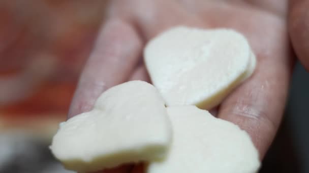 Stendere le fette di mozzarella a forma di cuore sulla pasta della pizza. Preparare una pizza al tonno a forma di cuore per San Valentino per una persona cara. Video 4K. Scatto artistico — Video Stock