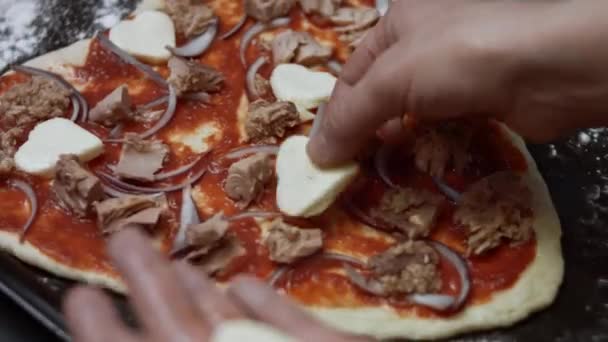 A szív alakú mozzarella szeleteket szór pizza tésztára. Szívalakú tonhal pizzát készítek Valentin-napra egy szerettemnek. 4K videó. — Stock videók