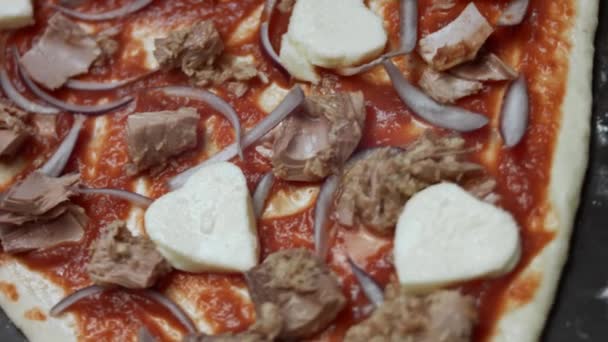 Macro vista di pasta pizza a forma di cuore con ingredienti. Preparare una pizza al tonno a forma di cuore per San Valentino per una persona cara. Video 4K. Vista dall'alto, rotazione — Video Stock