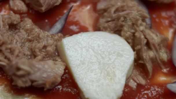 Makroaufnahme eines herzförmigen Pizzateigs mit Zutaten. Herzförmige Thunfisch-Pizza zum Valentinstag für einen geliebten Menschen zubereiten. 4K-Video. Draufsicht, Rotation — Stockvideo