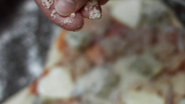Распространение сыра пармиджано по тесту пиццы с другими ингредиентами. Подготовка пиццы с тунцом в форме сердца к Дню Святого Валентина для любимого человека. 4K видео — стоковое видео