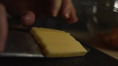 Kesme tahtasının bir parçasını peynire dilimlemek. Evde mutfakta yengeç çubuğu, peynir, salatalık, konserve mısır ve yumurta salatası hazırlıyorum.