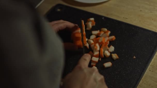 Frau schneidet Krabbenstangen für Salat auf einem Schneidebrett. Zubereitung von Salat aus Krabbenstangen, Käse, Gurken, Maiskonserven und Eiern in der heimischen Küche — Stockvideo