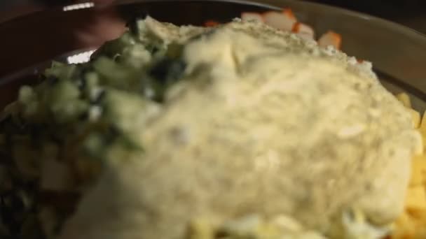 Krab salade ingrediënten in een glazen kom, mengen van ingrediënten. Bereiden van salade van krab, kaas, komkommer, maïs en eieren in blik in de keuken thuis — Stockvideo