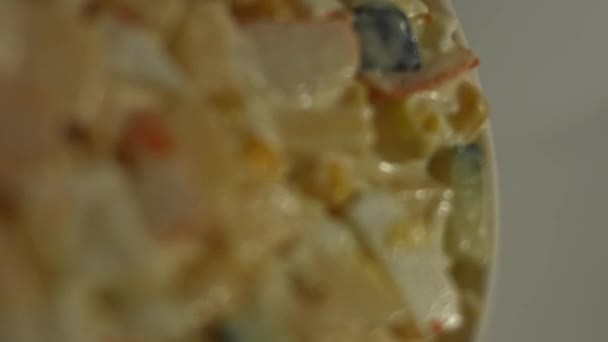 Vista macro de salada de caranguejo em uma chapa. Salada de palitos de caranguejo, queijo, pepino, milho enlatado, maionese e ovos na cozinha em casa — Vídeo de Stock