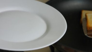 Fırında tavada pişmiş iki dilim tost ve beyaz bir tabağın üzerine koyun. Evde lezzetli tostlar pişirmek. 8 Mart 'ta sürpriz bir kahvaltı hazırlıyorum.