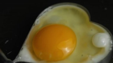 Kızartma tavasında kalp şeklinde kızarmış yumurta pişirmek. 8 Mart 'ta sürpriz kahvaltı hazırlıyorum. Makro görünüm