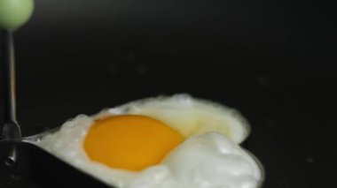 Kızartma tavasında kalp şeklinde kızarmış yumurta pişirmek. Kızarmış yumurtanın üzerine tuz dök. 8 Mart 'ta sürpriz bir kahvaltı hazırlıyorum.