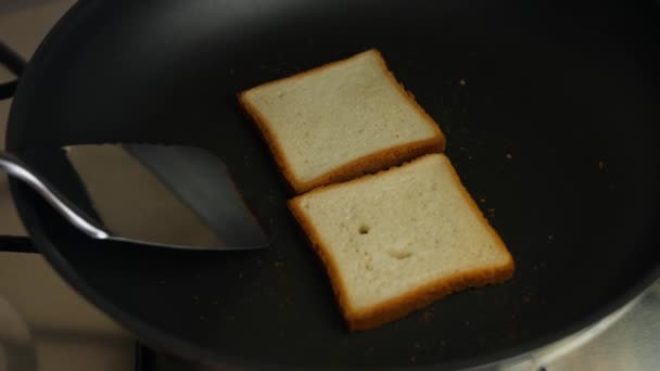 Dos rebanadas de tostadas volteadas en una sartén en la estufa. Cocinar deliciosos brindis en casa. Cocinar un desayuno sorpresa para marzo, 8 — Vídeo de stock