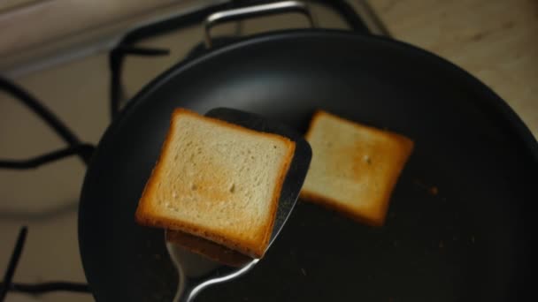 Twee plakjes toast gekookt in een pan op het fornuis en overboord gegooid. Heerlijke toastjes thuis koken. Een verrassingsontbijt koken voor 8 maart. Artistieke schietpartij — Stockvideo