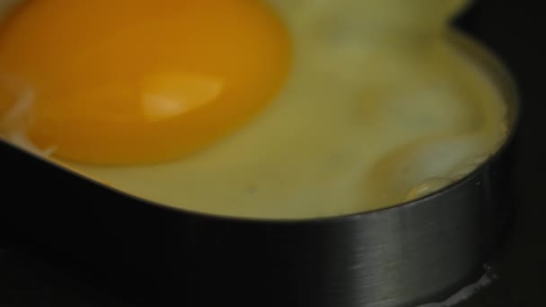 Koka stekt ägg i form av hjärta i en stekpanna. Matlagning en överraskning frukost för Mars, 8. Makroutsikt — Stockvideo