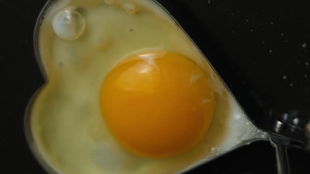 Koka stekt ägg i form av hjärta i en stekpanna. Matlagning en överraskning frukost för Mars, 8. Makro och ovanifrån — Stockvideo