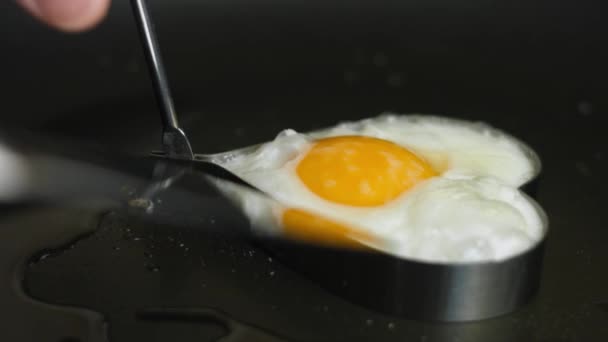 Koka stekt ägg i form av hjärta i en stekpanna. Lägger ägget på en tallrik. Matlagning en överraskning frukost för Mars, 8 — Stockvideo