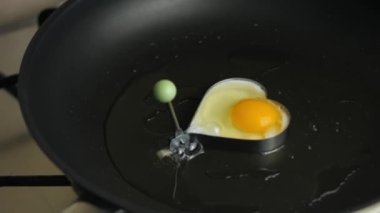 Kızartma tavasında kalp şeklinde kızarmış yumurta pişirmek. Kızarmış yumurtanın üzerine tuz dök. 8 Mart 'ta sürpriz bir kahvaltı hazırlıyorum.