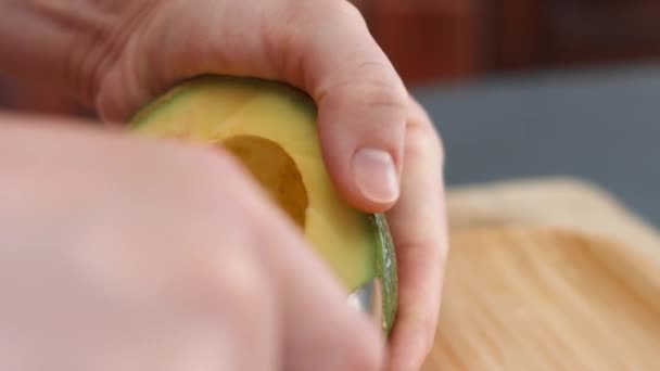 As mãos femininas retiram a casca de um abacate com uma colher. Cozinhar um café da manhã surpresa para março, 8 — Vídeo de Stock