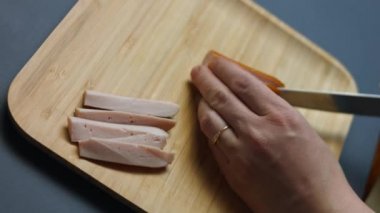 Tahta bir kesme tahtasının üzerinde sulu et sosisleri kesiyorum. 8 Mart 'ta sürpriz bir kahvaltı hazırlıyorum.