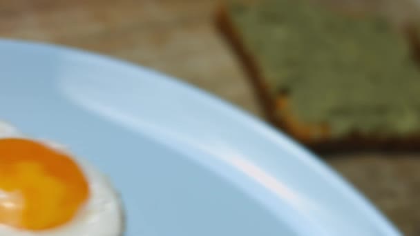 Poner huevos en forma de corazón en tostadas con aguacate machacado sobre una tabla de madera. Cocinar un desayuno sorpresa para el 8 de marzo. Vista macro — Vídeo de stock