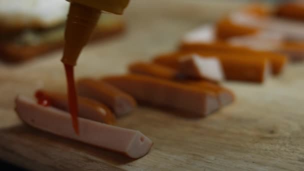 Verter la salsa de tomate sobre la palabra marzo formada por jugosas rebanadas de salchichas de carne en una tabla de cortar de madera. Cocinar un desayuno sorpresa para marzo, 8 — Vídeo de stock