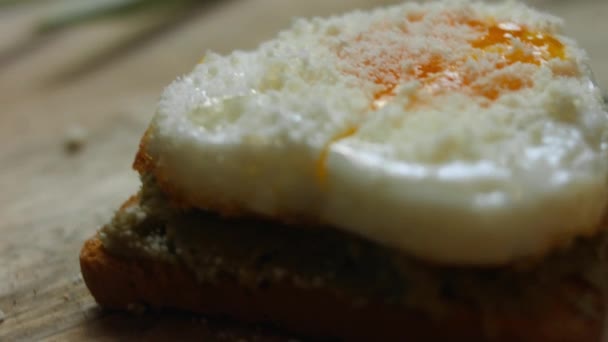 Herzförmige Eier auf Toastbrot mit zertrümmerter Avocado und Parmigiano auf einem Holzbrett. Kochen eines Überraschungsfrühstücks für den 8. März. Rotation — Stockvideo