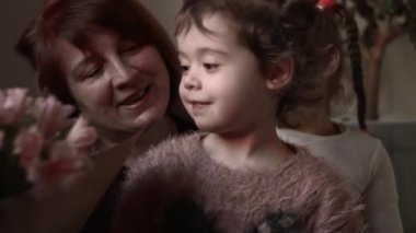 Güzel küçük kızlar çiçek verir. Torunlar büyükannelerine çiçek ve kucak verir..