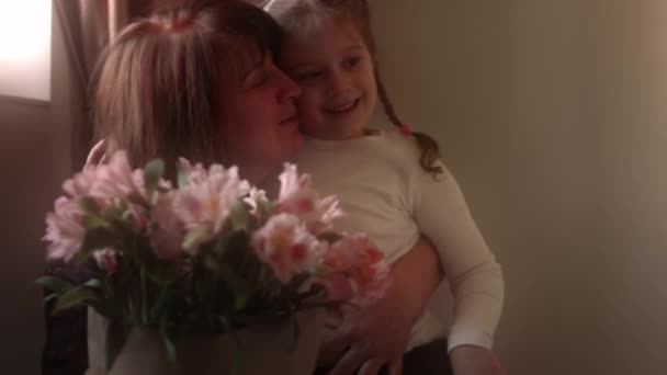 En vacker 5 år. Flickan ger blommor. Barnbarn ger blommor och kramar till sin mormor. Långsamma rörelser — Stockvideo