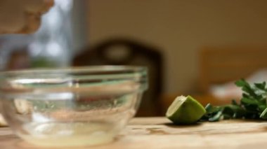 Dişi eller taze limon sıkar. Bir damla limon suyu cam kaseye düşer. Salsa yapma süreci