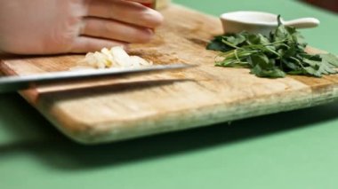 Doğranmış domateslere doğranmış sarımsak ekliyorum. El blender bardağına. Salsa yapma süreci