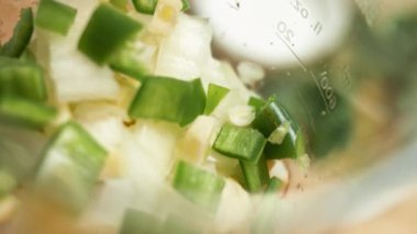 El blender bardağında salsa sosu için kesilmiş malzemelerin makro görüntüsü. Salsa yapma süreci. Yavaş çekim