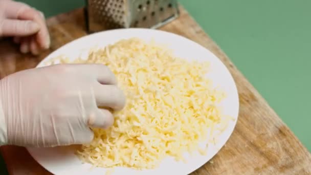 Chefs hand arranging a big pile of grated cheese on a white plate. Process of making quesadillas — Stock Video