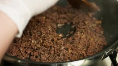 Kızartma tavasında pişen kıymaya taze kırmızı dolmalık biber ekliyorum. Tahta bir spatulayla karıştırıyorum. quesadillas yapma süreci