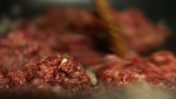 牛ひき肉と玉ねぎのみじん切りとフライパンでニンニク料理.木製のへらと混合します。ケサディラを作る過程。マクロ — ストック動画