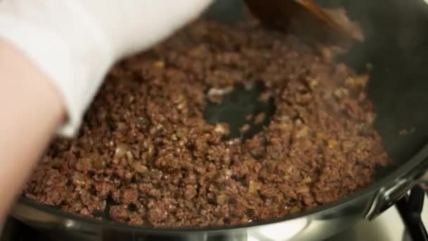 Adding chopped fresh red bell pepper to ground beef cooking on a frying pan. Mixing with a wooden spatula. Process of making quesadillas — Stock Video