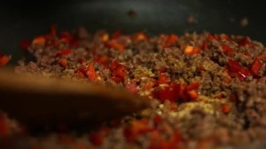 Bifteğe Meksika baharatı ve kızartma tavasında pişen kırmızı dolmalık biber ekliyorum. Tahta bir spatulayla karıştırıyorum. quesadillas yapma süreci