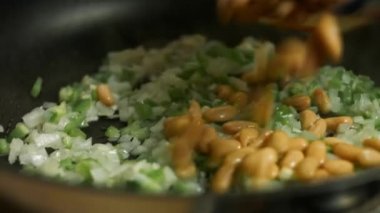 Tavada kızartılan taze yeşil dolmalık biber, soğan ve sarımsağa konserve fasulye ve mısır ekliyorum. quesadillas yapma süreci
